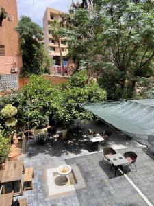 an outdoor patio with tables and chairs and trees at Hôtel Résidence Marrakech in Marrakesh
