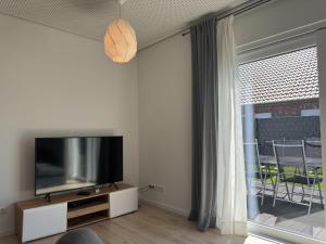 a living room with a flat screen tv next to a window at Moderne Ferienwohnung mit Sauna & Terrasse in Burhave