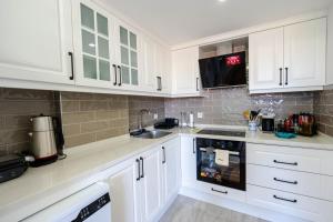 a white kitchen with white cabinets and a sink at Luna in Dalaman