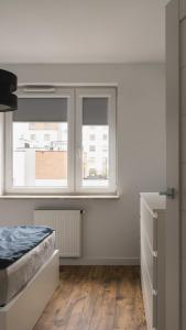 a bedroom with a bed and two windows at BEMO Apartment in Warsaw