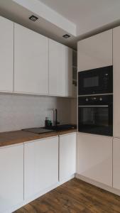 a kitchen with white cabinets and a black microwave at BEMO Apartment in Warsaw