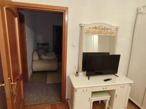 a room with a television on a desk and a mirror at Vila Elena in Bucharest