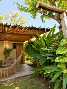 a wooden porch with a hammock in a garden at Pousada Vila Verde Vila de Caraíva in Caraíva