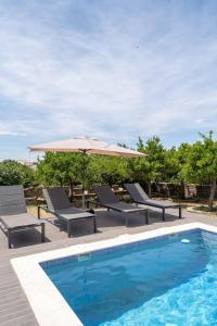 a swimming pool with chairs and an umbrella and a swimming pool at Casa do Loureiro in Alandroal