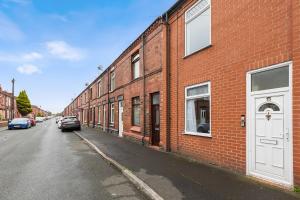 a red brick building with a white door on a street at Haydock Contractor House, 2-Bed, Easy M6 Access in Haydock