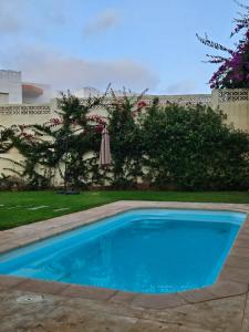 a blue swimming pool in a yard with an umbrella at Ocean Rooftop Hotel in Ben Slimane