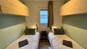 two beds in a small room with a window at Cube & Quiet - Where nature meets comfort in Haarle