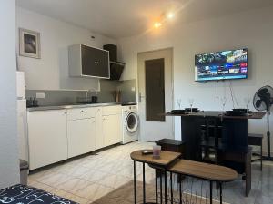 a kitchen with white cabinets and a table and a tv at Studio avec piscine à 1km de la plage in Cavalaire-sur-Mer