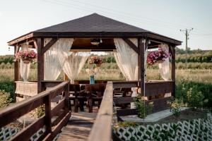 a wooden gazebo with a table and flowers at Nad Andruszkowianką in Andruszkowice