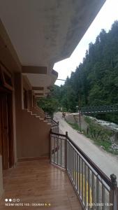 a balcony of a building with a view of a road at Tirthan river edge in Bathād
