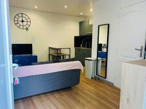 a room with a bed and a kitchen with a clock on the wall at Cosy Paris CDG Stade de France in Le Blanc-Mesnil