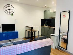 a room with a kitchen with a clock on the wall at Cosy Paris CDG Stade de France in Le Blanc-Mesnil