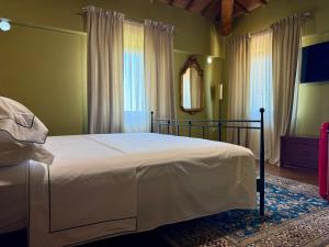ein Schlafzimmer mit einem Bett mit weißer Bettwäsche und einem Spiegel in der Unterkunft Sacro e Profano Albania in Zikxhafaj