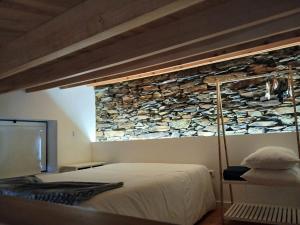 a bedroom with a bed and a stone wall at Casa do Avô Alváro - Refugio do Rei in Casal do Rei