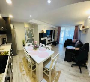 a kitchen and living room with a white table and chairs at Saturn Cozy Stay in Mangalia