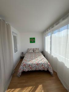 a bedroom with a bed with a floral bedspread and a window at Parenthèse nature à Prémanon in Prémanon