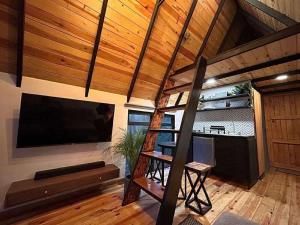 a loft bed in a room with a flat screen tv at Cabañas Bosque Antiguo in Tapalpa