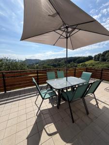 a table and chairs with an umbrella on a patio at Gîte la Tinou in Saint-Nabord