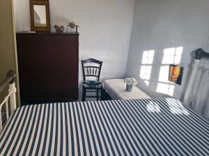 a bedroom with a bed and a chair in a room at Mylopotamos House in Milopótamos