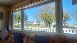 a large window in a living room with a couch at 1 The Willows Reighton Sands in Reighton