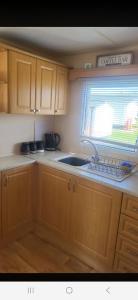 a kitchen with wooden cabinets and a sink and a window at 1 The Willows Reighton Sands in Reighton