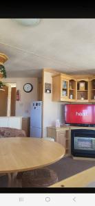 a kitchen with a table and a refrigerator and a tv at 1 The Willows Reighton Sands in Reighton +6 photos