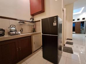 a kitchen with a black refrigerator and a sink at Nafaka Hostel and Tours in Malang