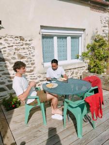 two men sitting at a table on a patio at Charmant gite en pierre in Gratot