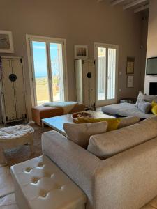a living room with couches and a table and windows at Ellie Villa Seaside Koufonisi in Nisída Koufonísion