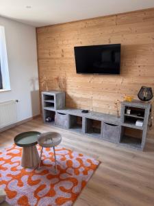 a living room with a flat screen tv on a wall at Gîte la Tinou in Saint-Nabord