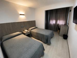 a hotel room with two beds and a window at Hostal Goyma I in San Fernando de Henares