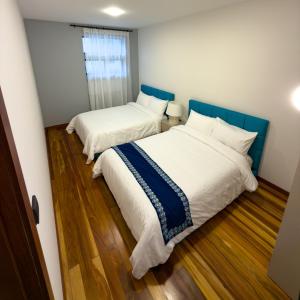 two beds in a small room with wooden floors at Arbórea Casa Boutique in Cuenca