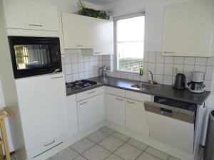 a white kitchen with a sink and a microwave at Bungalow in Breskens near Beach and Lighthouse in Breskens