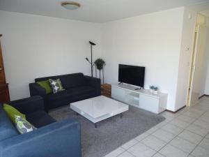 a living room with a couch and a tv at Bungalow in Breskens near Beach and Lighthouse in Breskens
