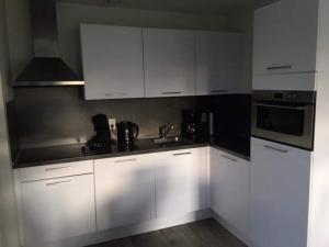 a kitchen with white cabinets and a sink at Holiday Home Breskens near the Coast in Breskens
