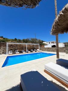 a swimming pool with chairs and an umbrella at Beba's Studios in Batsi