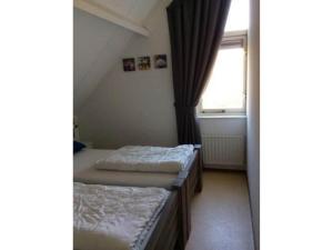 two beds in a room with a window at Bungalow in Breskens near Beach & Lighthouse in Breskens
