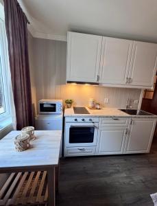 a white kitchen with white cabinets and a table at Bispen Villa Utsikten in Åndalsnes