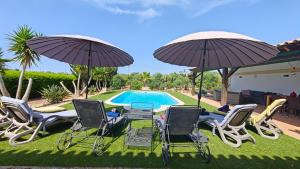 a group of chairs and umbrellas next to a pool at Quinta das Lameiras in Lagoa