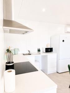 a white kitchen with a sink and a refrigerator at Gem on Matrix - Hidden Retreat with Deck in Lightning Ridge