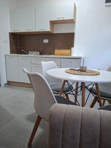 a white table and chairs in a room with a kitchen at Apartmani Ksenija Sofija in Igalo