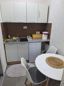 a small kitchen with a table and chairs and a sink at Apartmani Ksenija Sofija in Igalo +6 photos