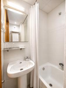 a white bathroom with a sink and a bath tub at Hostal Goyma II in San Fernando de Henares