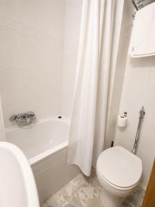 a white bathroom with a toilet and a bath tub at Hostal Goyma II in San Fernando de Henares