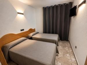 a hotel room with two beds and a television at Hostal Goyma II in San Fernando de Henares