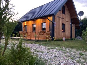 a wooden cabin with chairs in front of it at Leśny zakątek in Wisełka