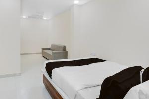 a white room with a bed and a chair at Hotel O RB Delight in Karīmnagar