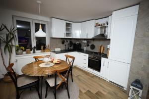 a kitchen with white cabinets and a wooden table at Nebeska Terasa in Knić