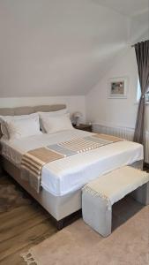a bedroom with a large white bed with a bench at Nebeska Terasa in Knić