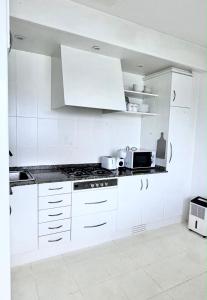 a white kitchen with white cabinets and a microwave at Cabanas da Auga A in A Telleira